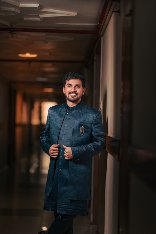 Free A young man in a stylish traditional Indian outfit smiles confidently in a dimly lit corridor. Stock Photo