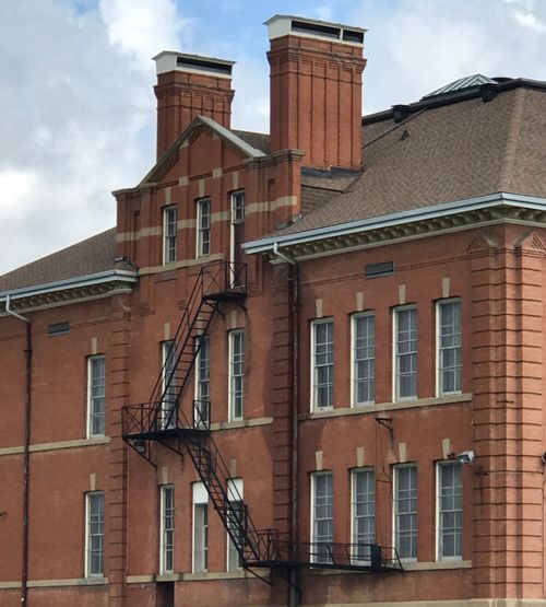 Free Red brick building with classic architecture and exterior fire escape staircase. Stock Photo