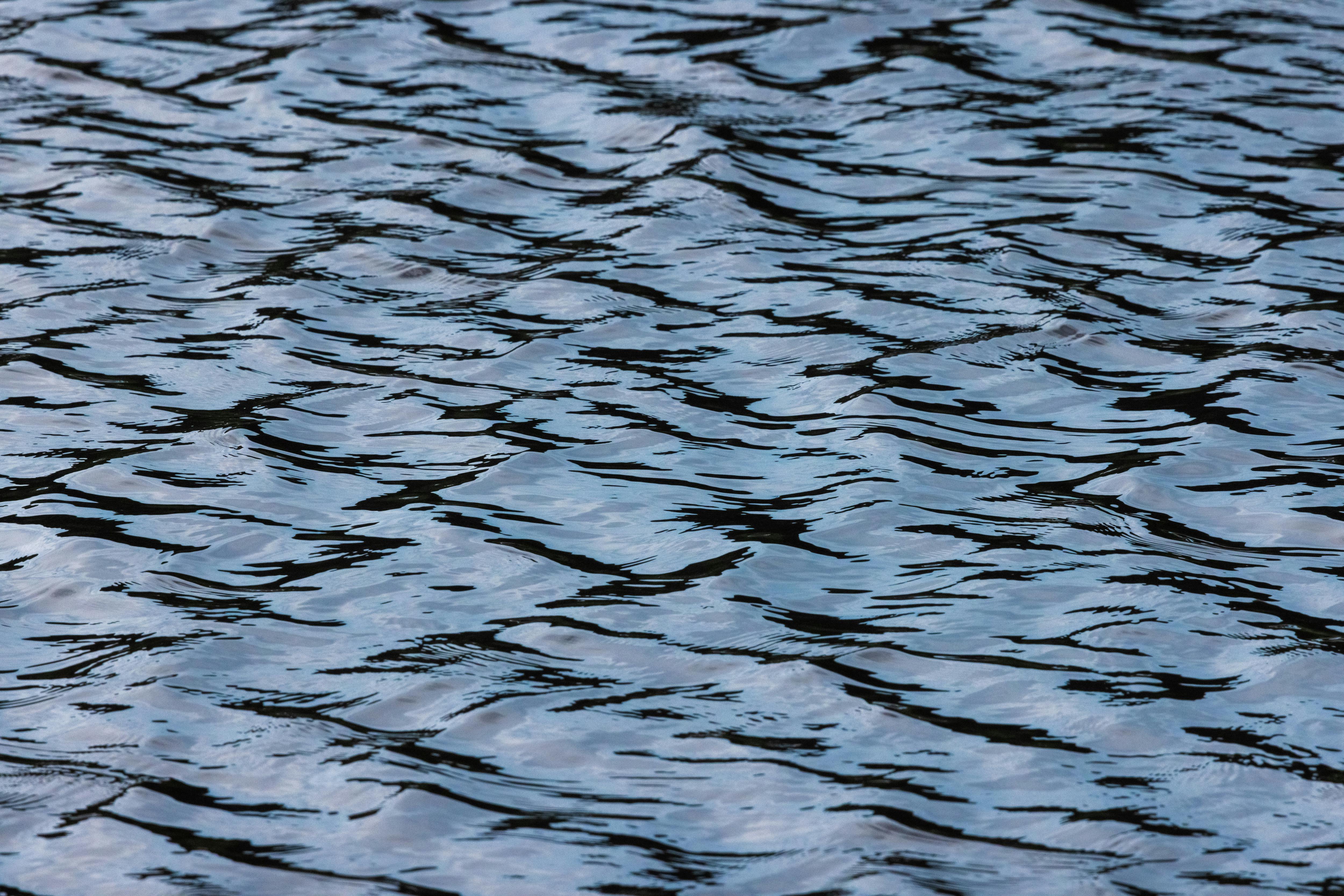 Free A detailed view of rippling water showing natural patterns and reflections. Stock Photo