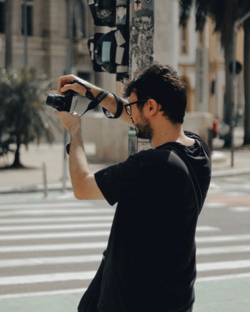 Free Man taking street photos in São Paulo with a camera on a sunny day. Stock Photo