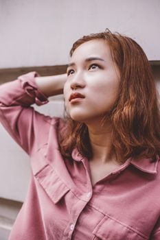 一名年轻女子身着粉色衬衫，若有所思地望向前方