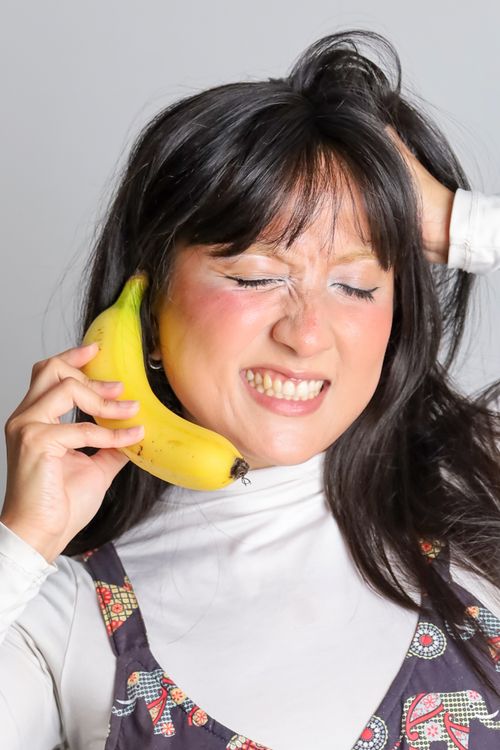 Free Young woman humorously using a banana as a phone. Stock Photo