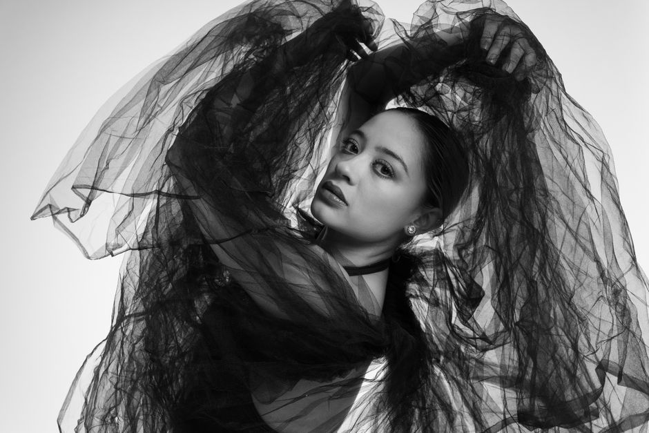 Black and white portrait of a Latina dancer with sheer fabric, exuding grace and poise.