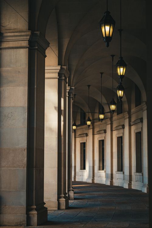 Free A beautifully lit neoclassical corridor in Washington DC showcasing architectural grace with its arches and lanterns. Stock Photo