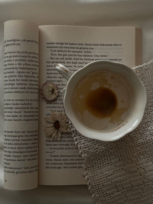 Free An open book with a half-empty coffee cup and dried flowers, creating a cozy scene. Stock Photo