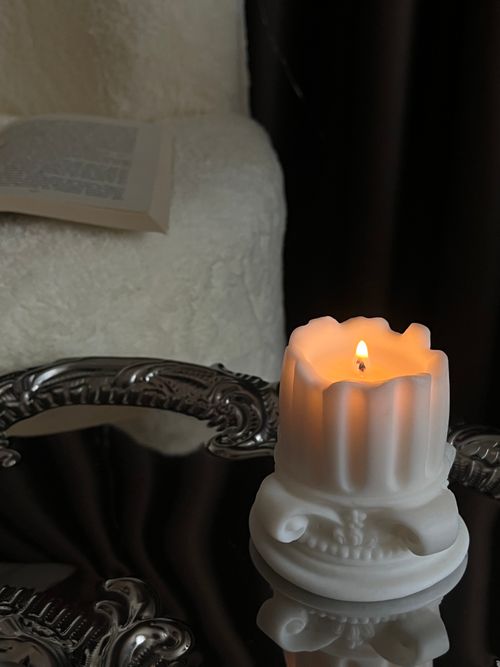 Free Cozy indoor scene with a candle burning atop an ornate table beside an open book. Stock Photo