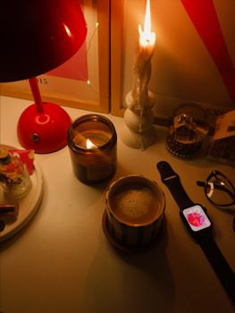 A warm and cozy desk setup with candles, a hot drink, and ambient lighting.