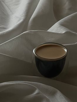 Stylish coffee cup on elegant draped fabric in a cozy setting.