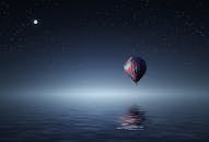 Red and Blue Hot Air Balloon Floating on Air on Body of Water during Night Time