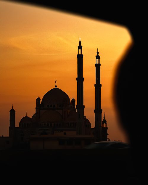 Free Silhouette of a mosque with tall minarets against a breathtaking sunset sky. Stock Photo