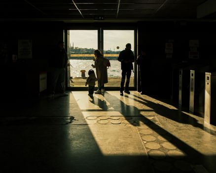 People silhouetted against bright terminal entrance with cityscape view beyond.