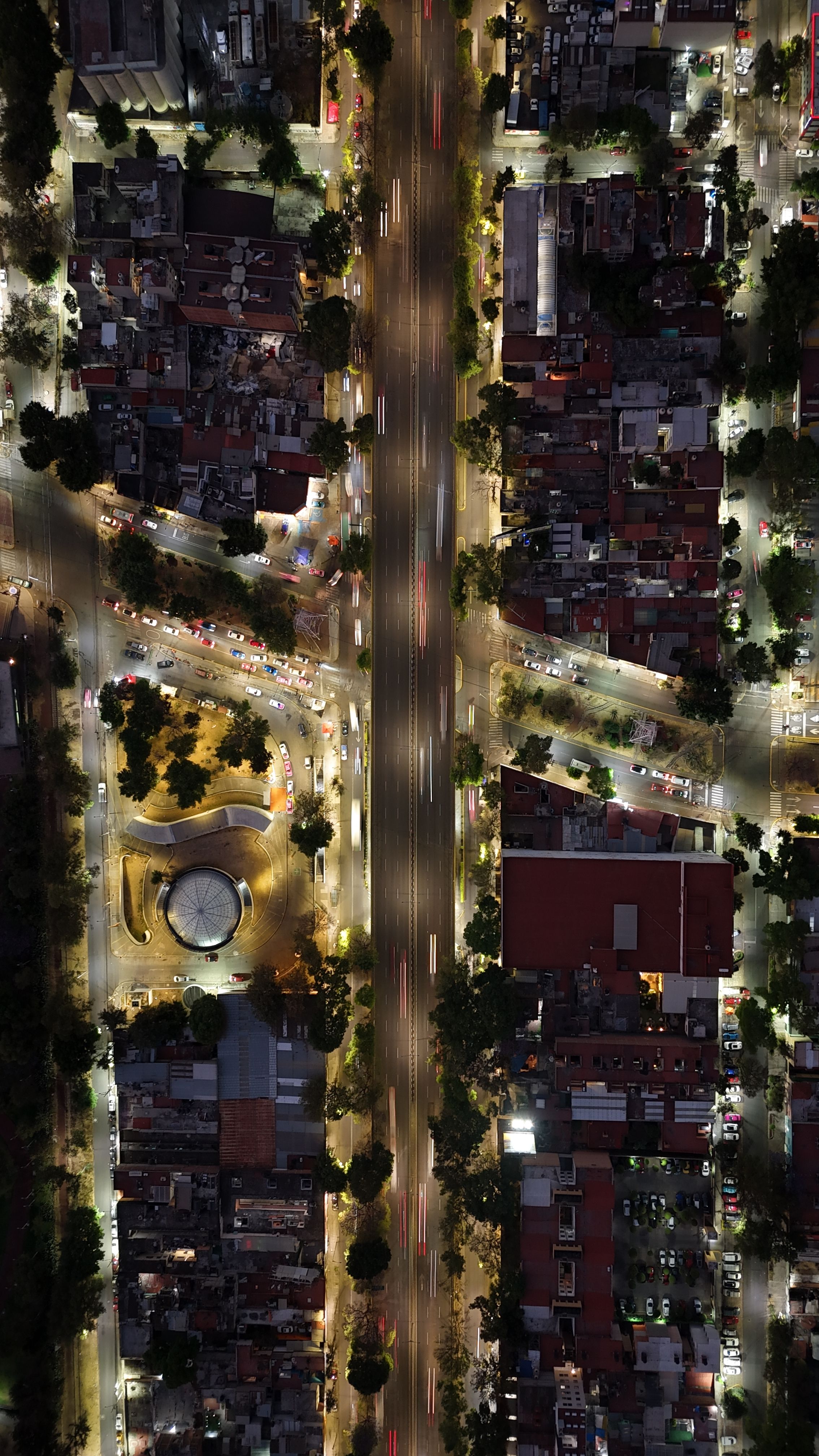 High-angle aerial shot capturing a vibrant urban intersection at night, showcasing city lights and traffic flow.