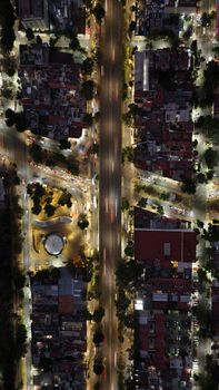 Top-down aerial view of illuminated city intersection at night, showcasing vibrant urban life.
