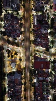 Dynamic aerial shot of vibrant urban streets at night with glowing trails and buildings.
