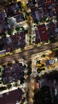 Aerial shot of illuminated city intersection at night highlighting busy urban layout.