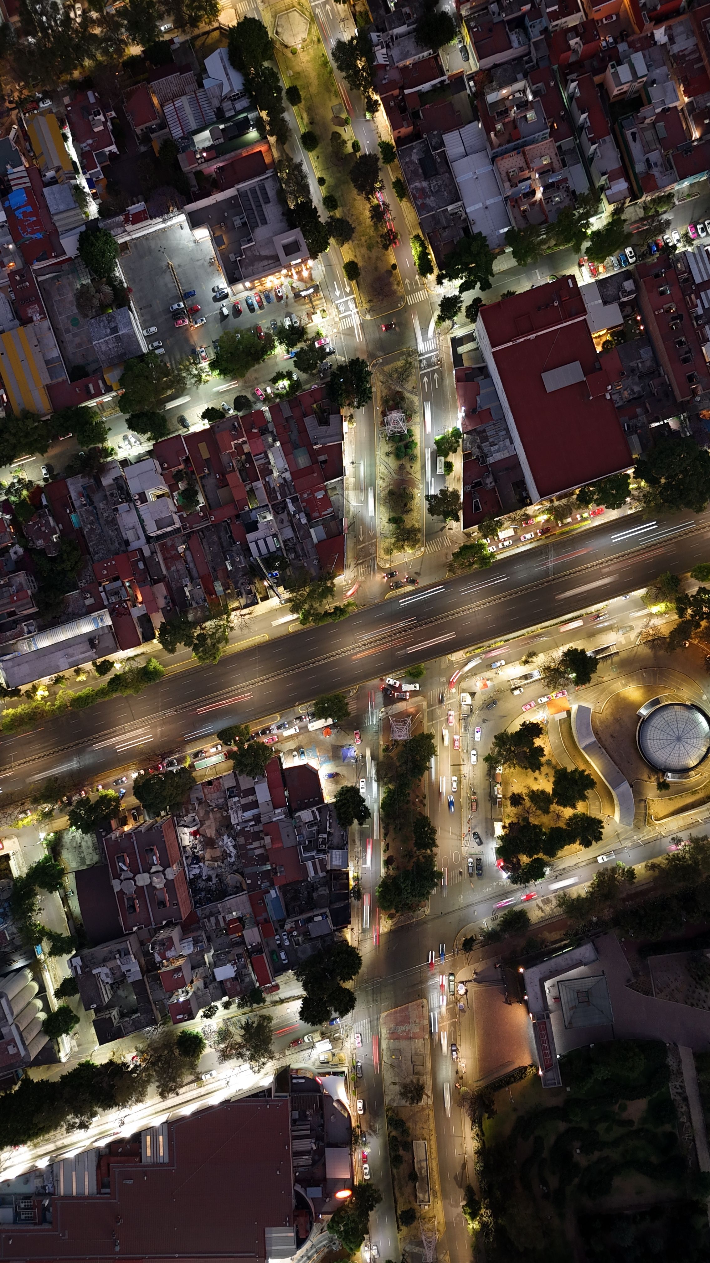 Stunning aerial view of an illuminated city intersection at night, highlighting urban architecture.