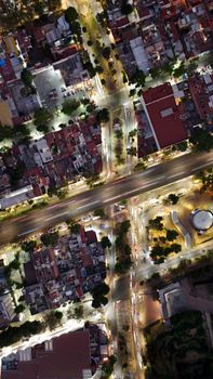 High-angle aerial view of a bustling city intersection at night, showcasing streets and buildings.