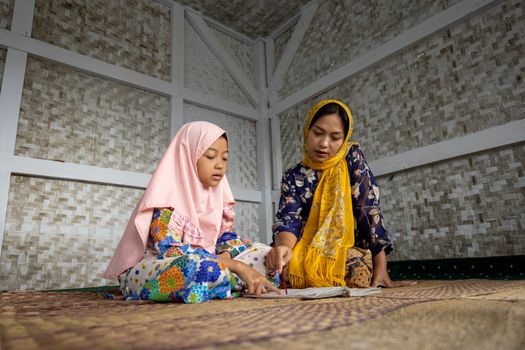 A mother and daughter study the Quran together at home in Bandung, Indonesia.