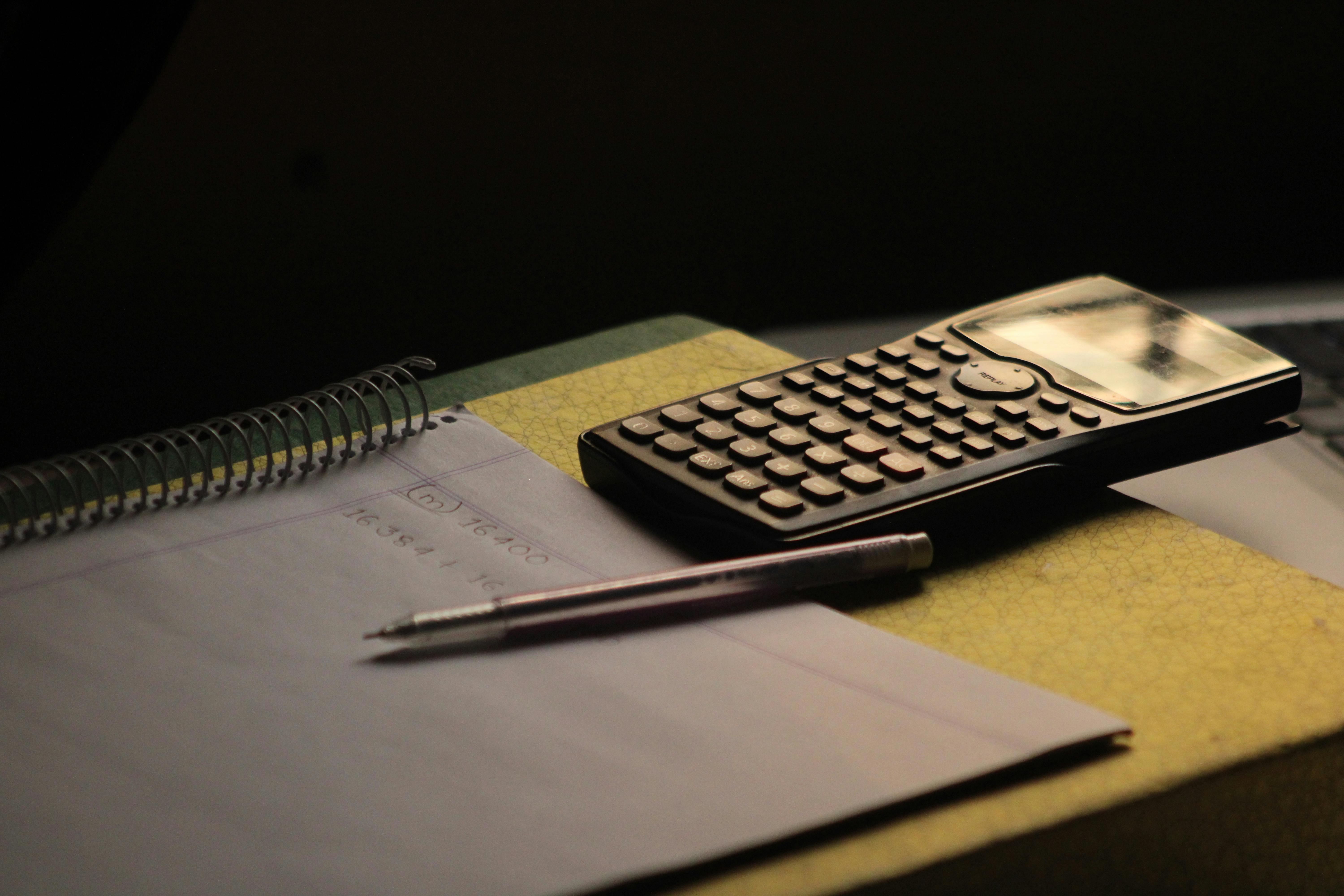 gratis Close-up van een rekenmachine en notitieboekje op een bureau. Ideaal voor educatieve thema's. Stockfoto