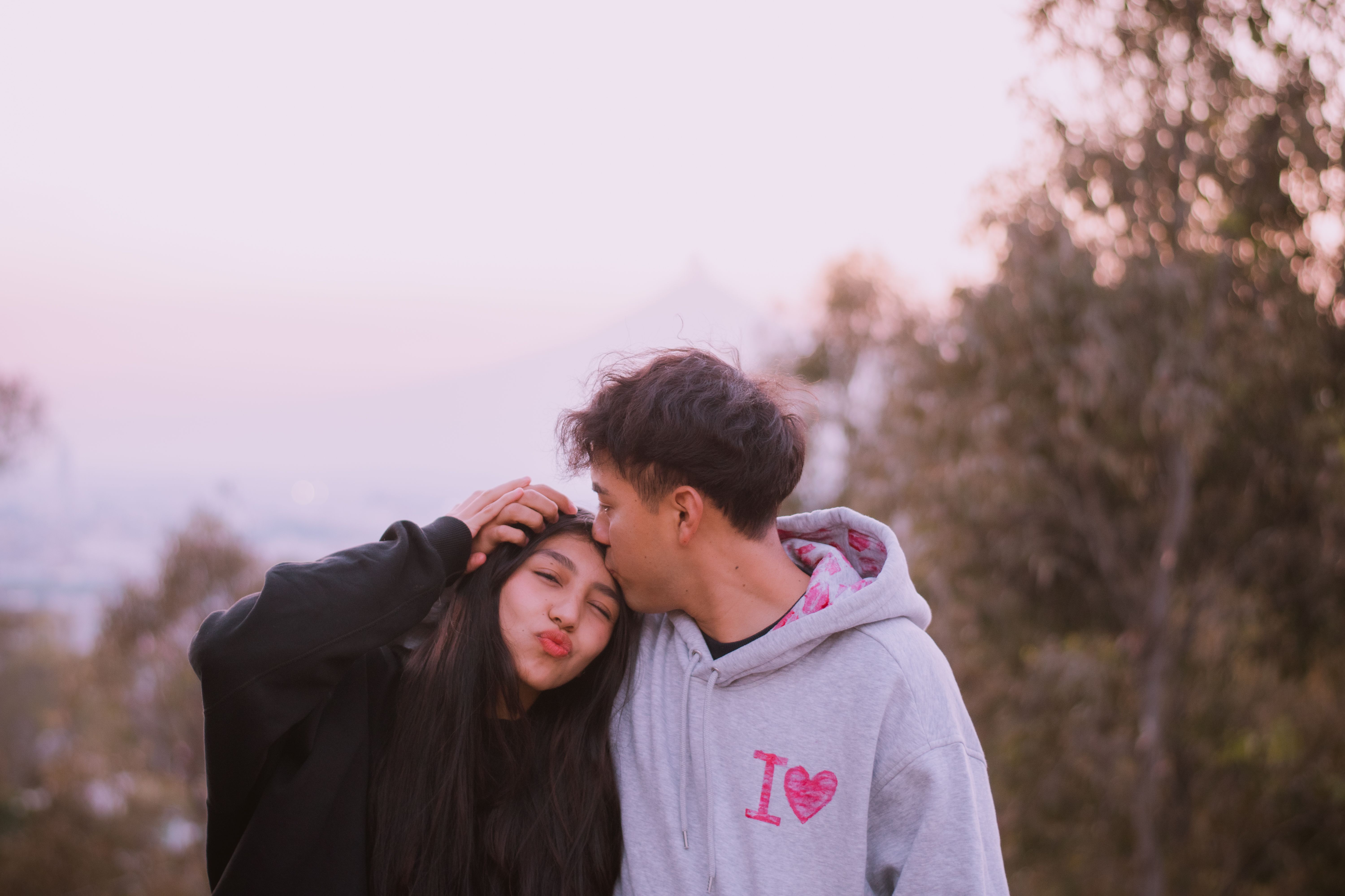 A young couple shares a tender moment outdoors during sunset, conveying love and affection.