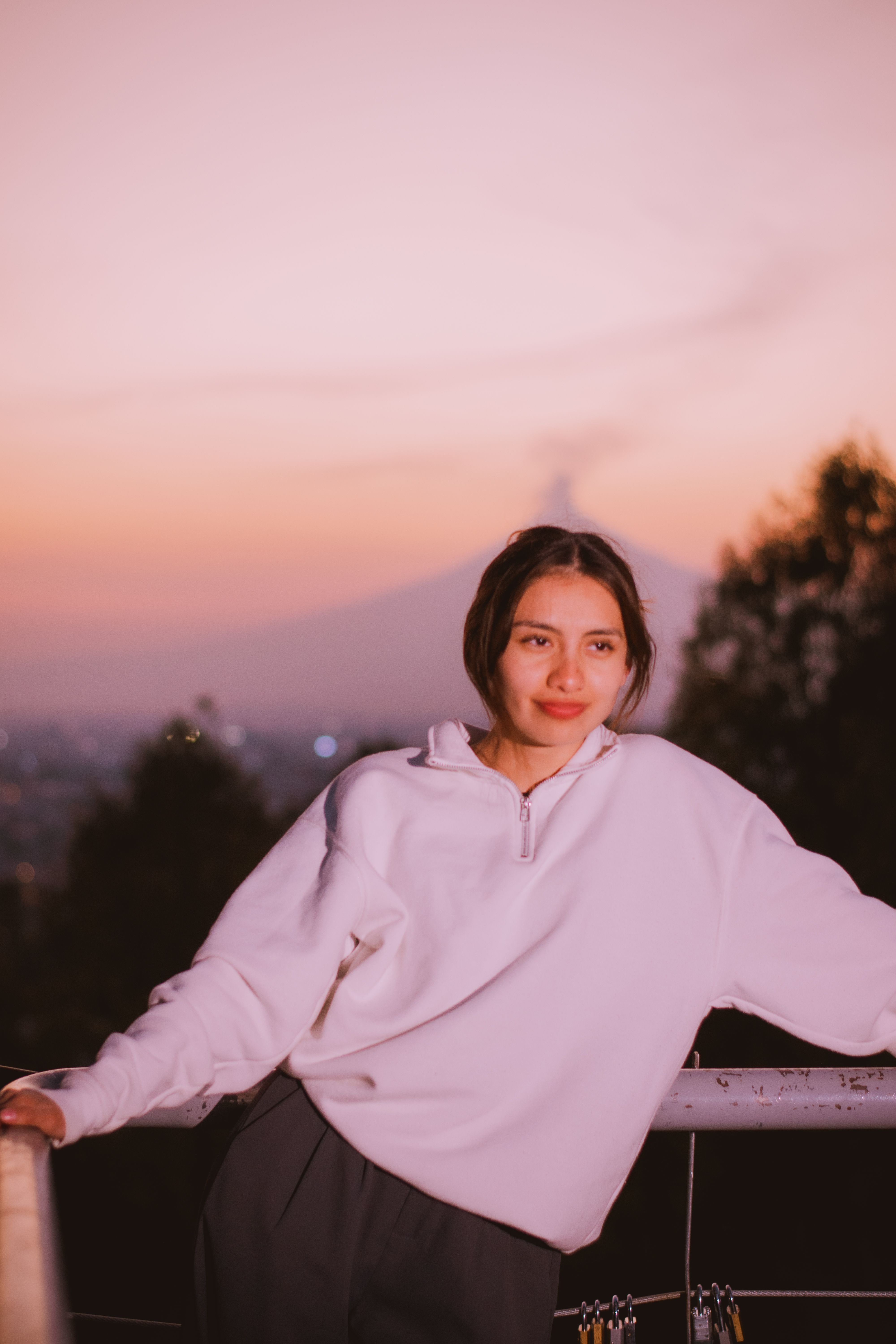 Serene portrait of a young woman enjoying a peaceful sunset with a mountain backdrop.