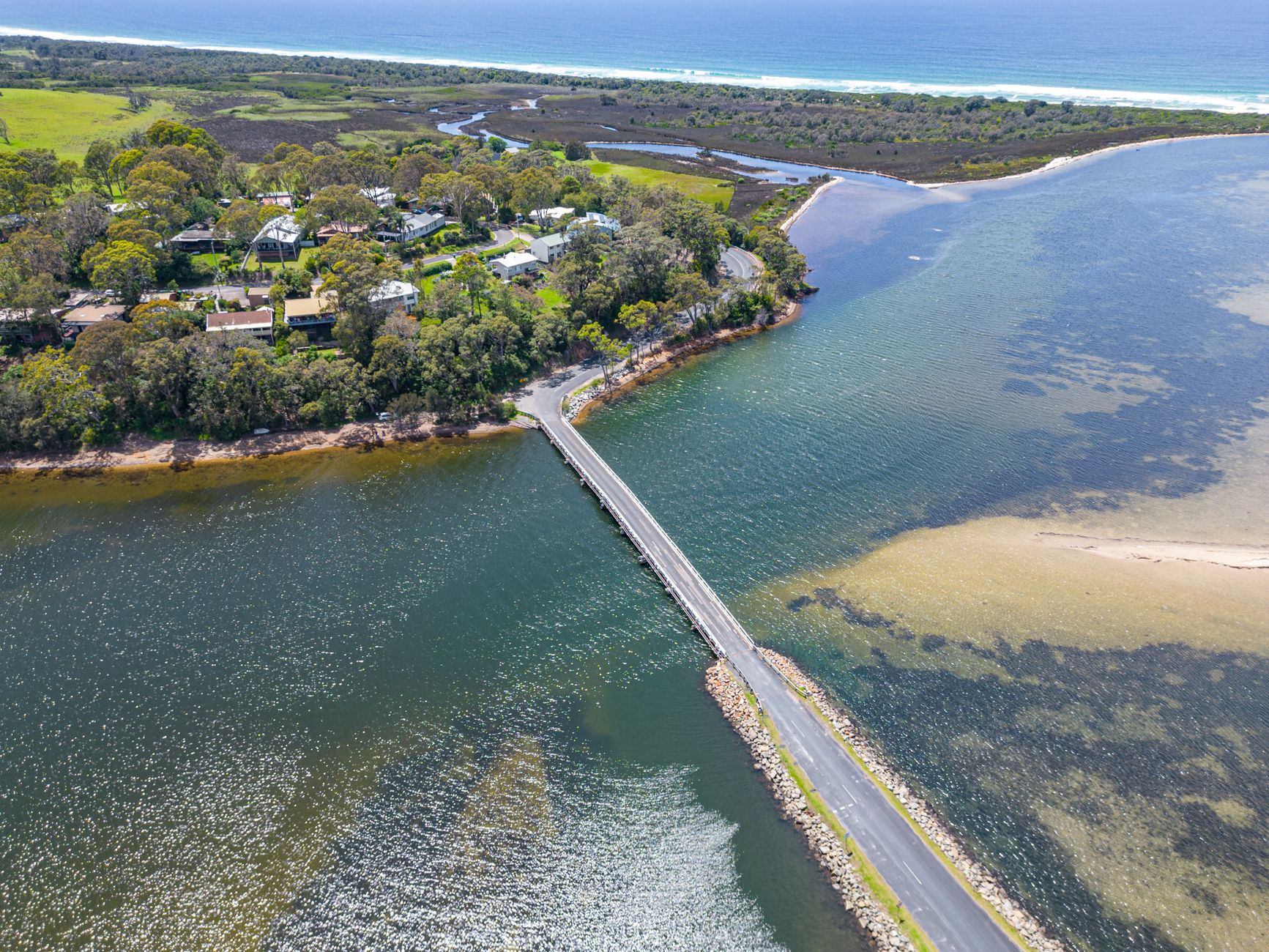 Scenic aerial photo of a bridge connecting lush landscape with a coastal road in Australia.