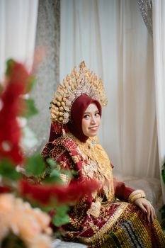 A Bugis bride in traditional Makassar wedding attire, adorned with gold accessories.