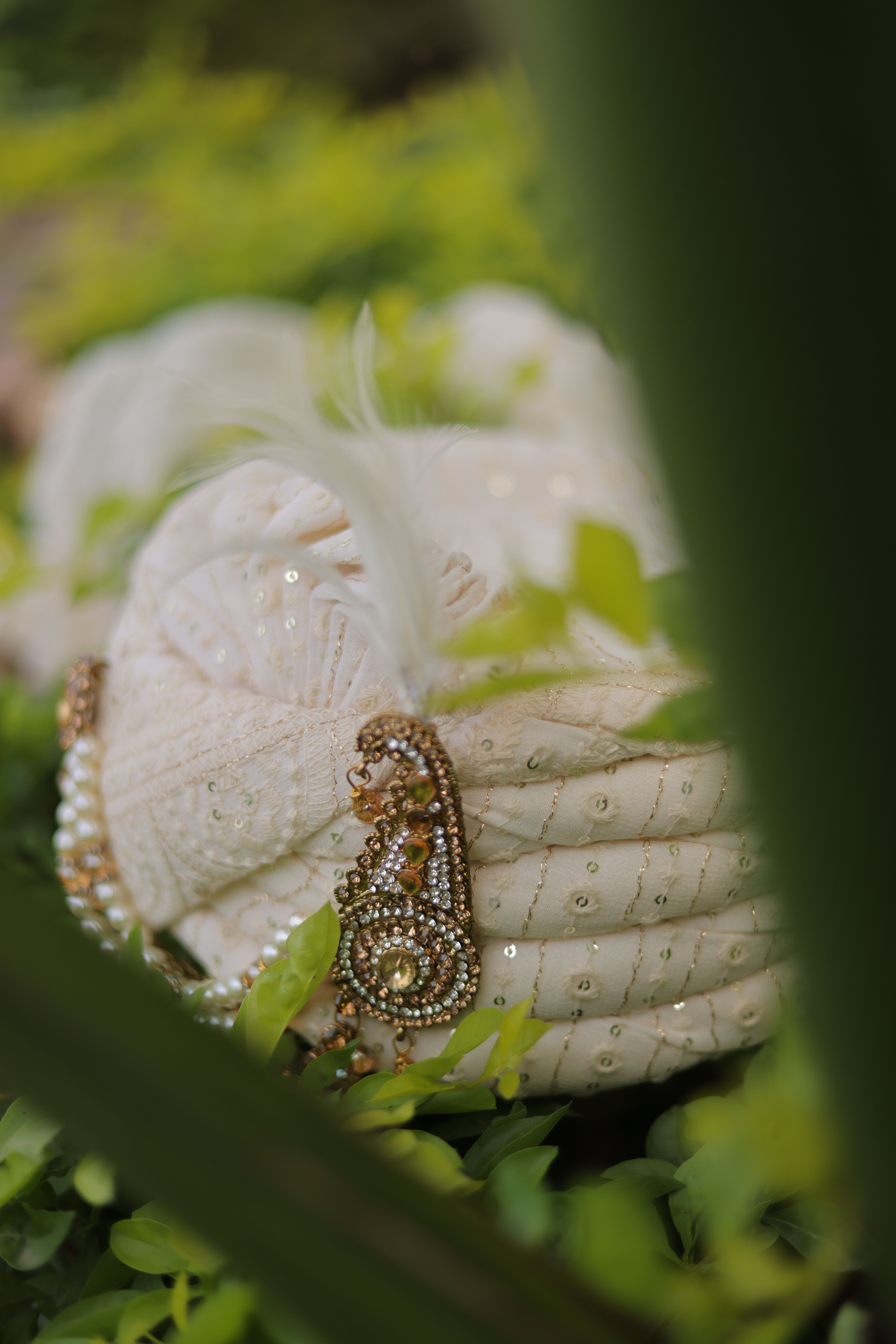 Close-up of an ornate Indian turban amidst green foliage, showcasing traditional craftsmanship.