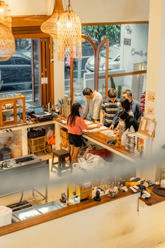 A cozy indoor cafe scene in Surabaya, Indonesia, with people interacting around a wooden table.