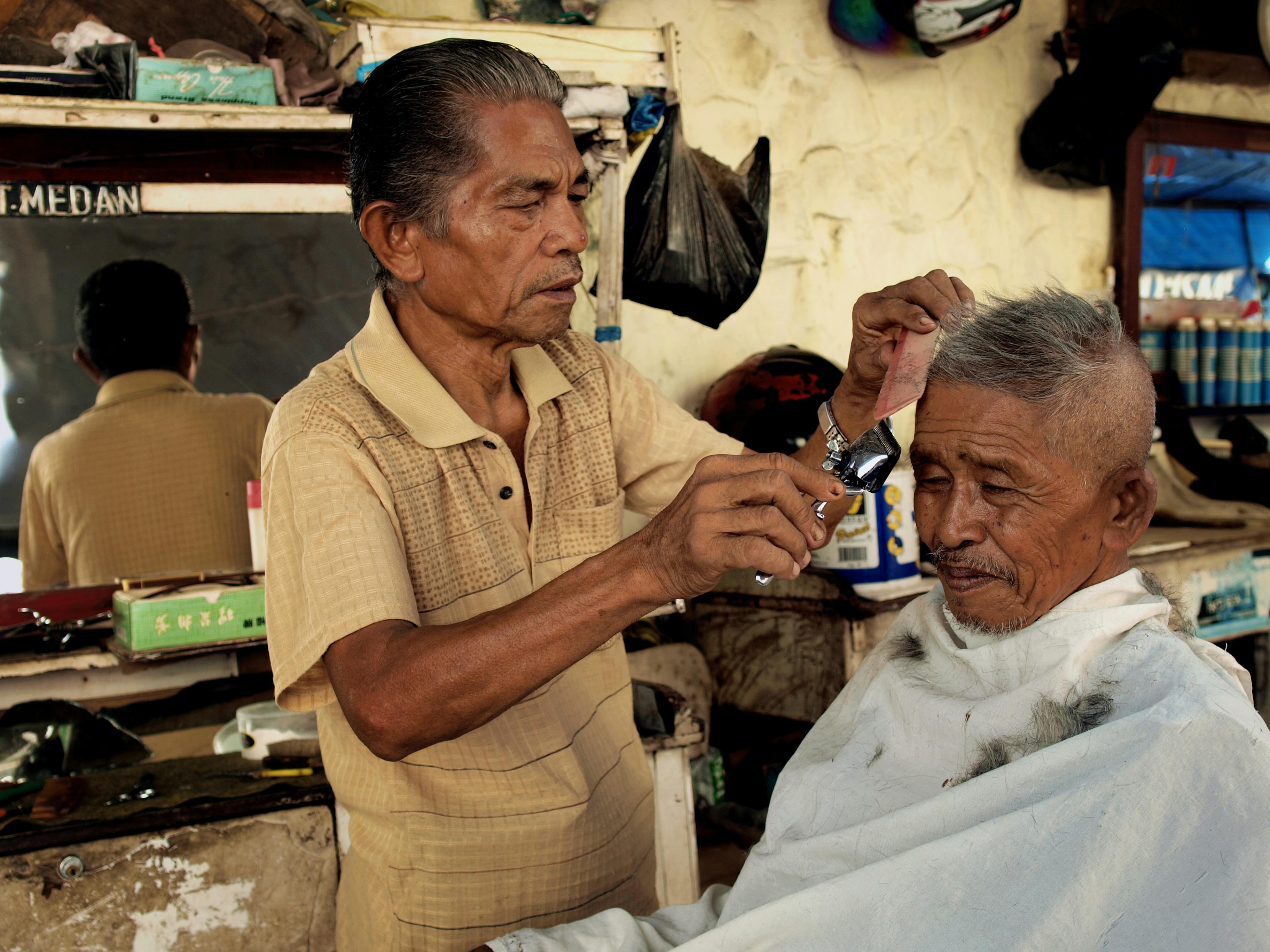 Two elderly men in a traditional barber shop in Sumatra, Indonesia.