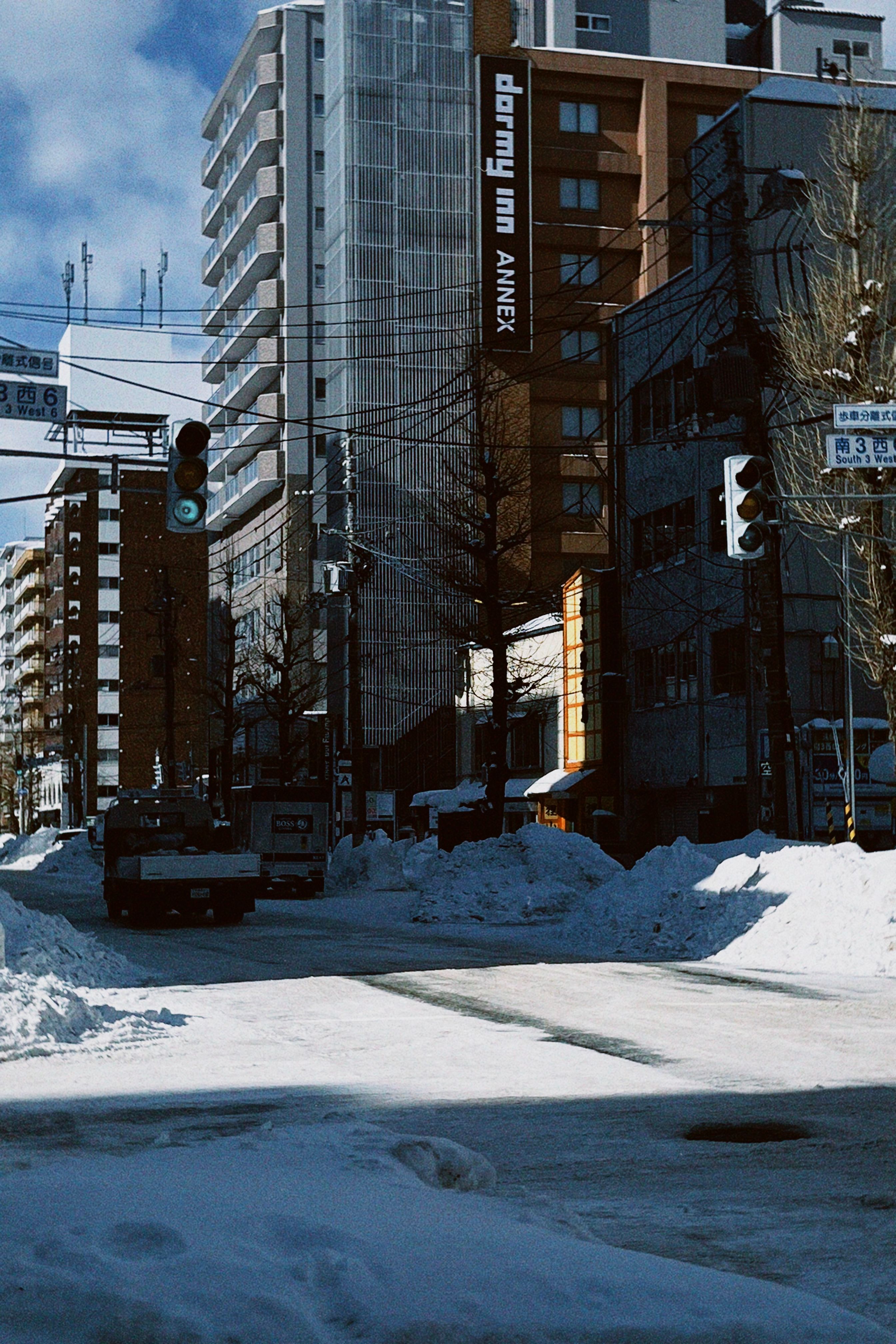 Snow-covered street in Sapporo, Japan with modern buildings and traffic lights.