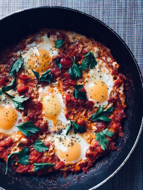 Free Overhead of delicious shakshuka with fried eggs and herbs in tomato sauce placed on table Stock Photo
