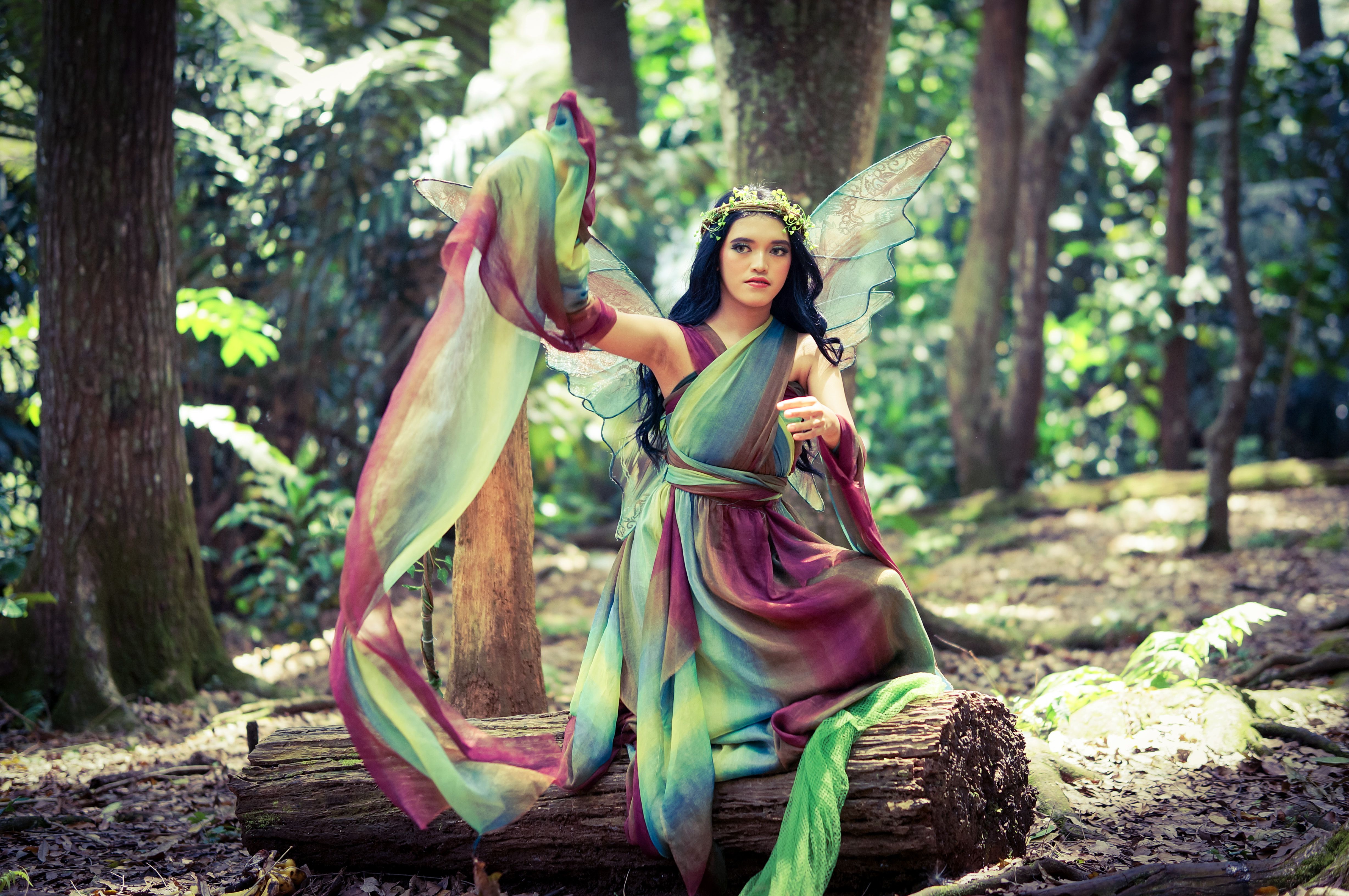 A mystical fairy in vibrant costume graces the lush Indonesian forest, embodying magic and fantasy.