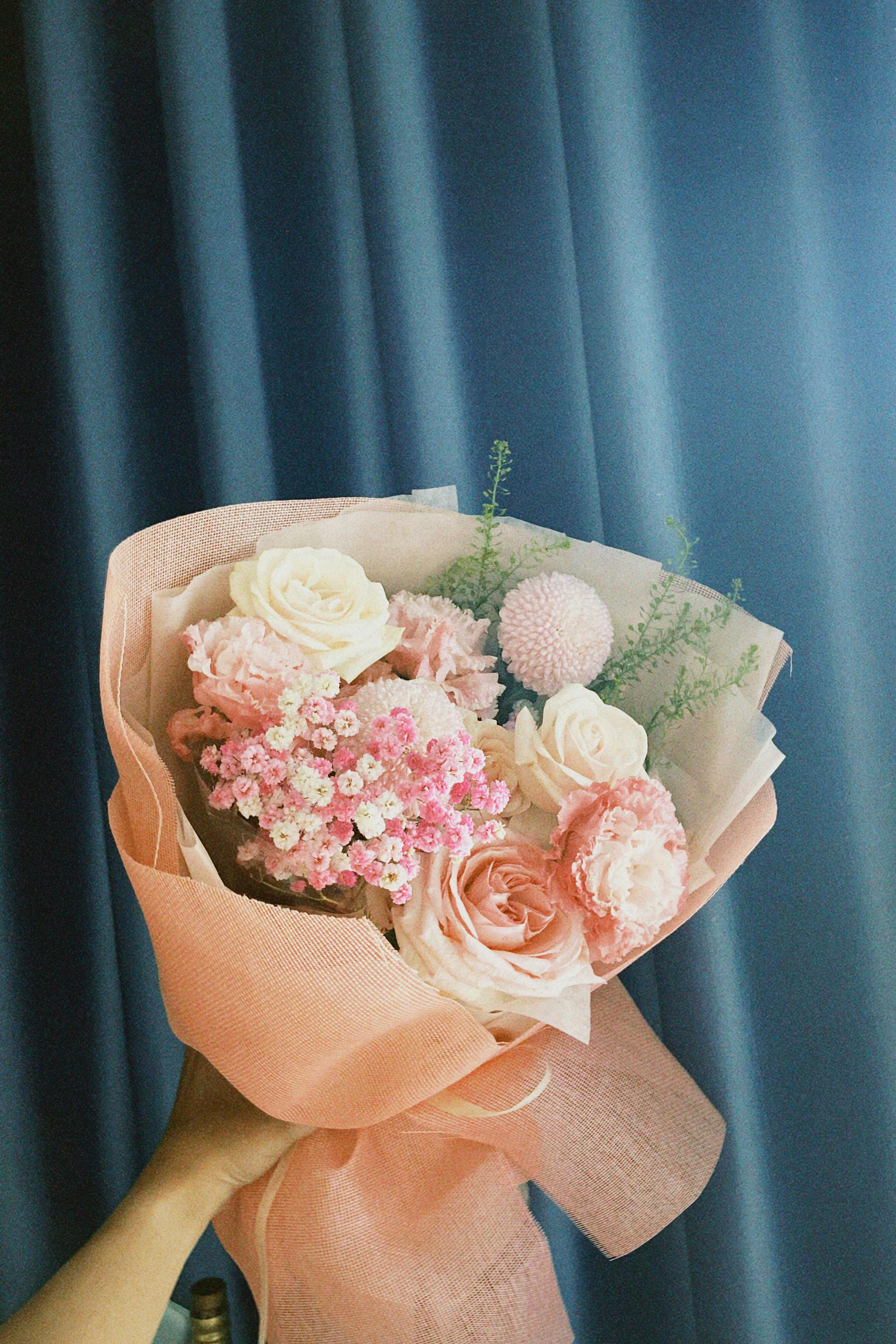 [ColoSach]-a-beautiful-bouquet-featuring-pink-roses,-carnations,-and-other-flowers-against-a-blue-backdrop.