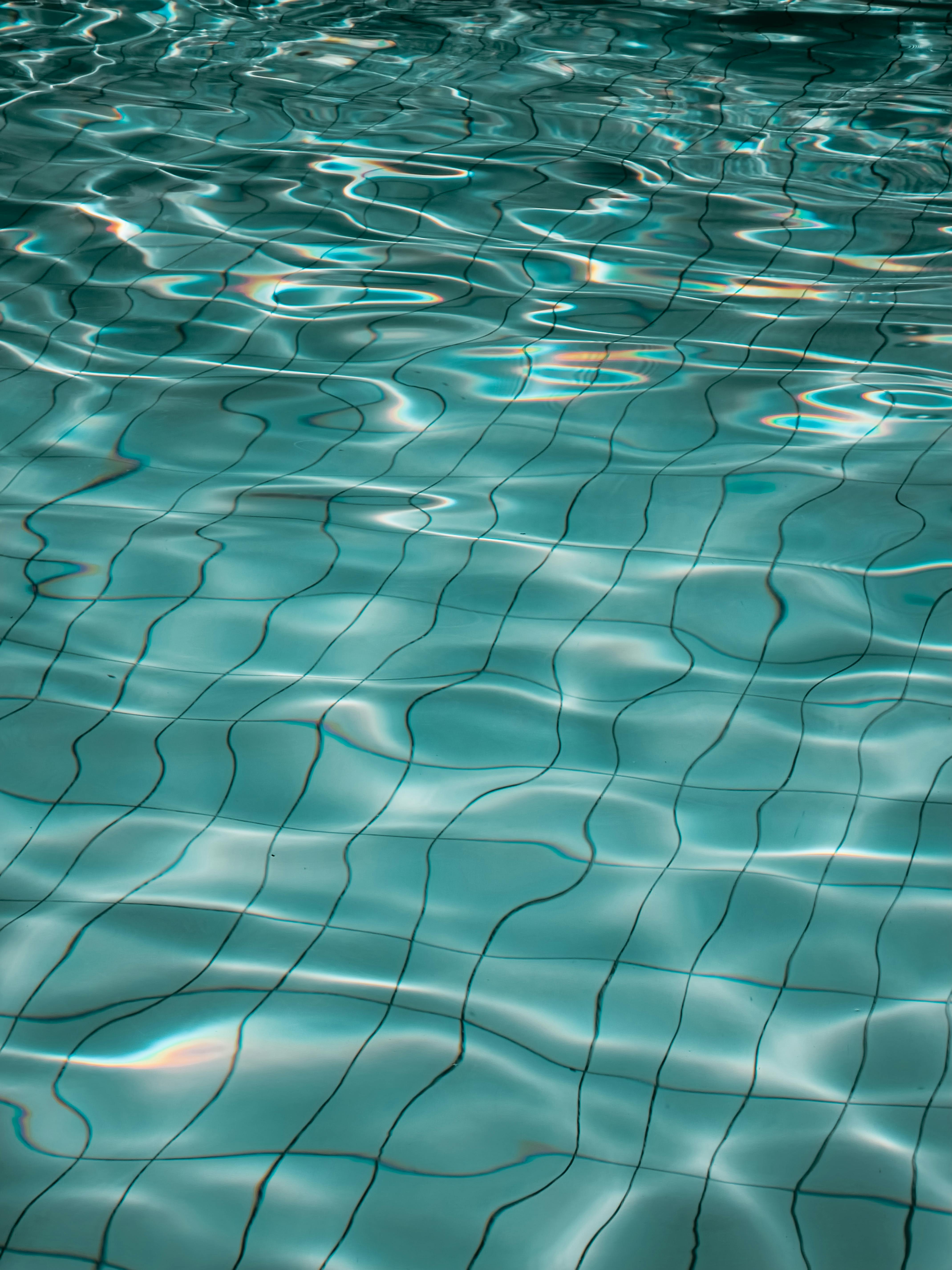 Serene image of a swimming pool's water surface with gentle ripples and reflections.