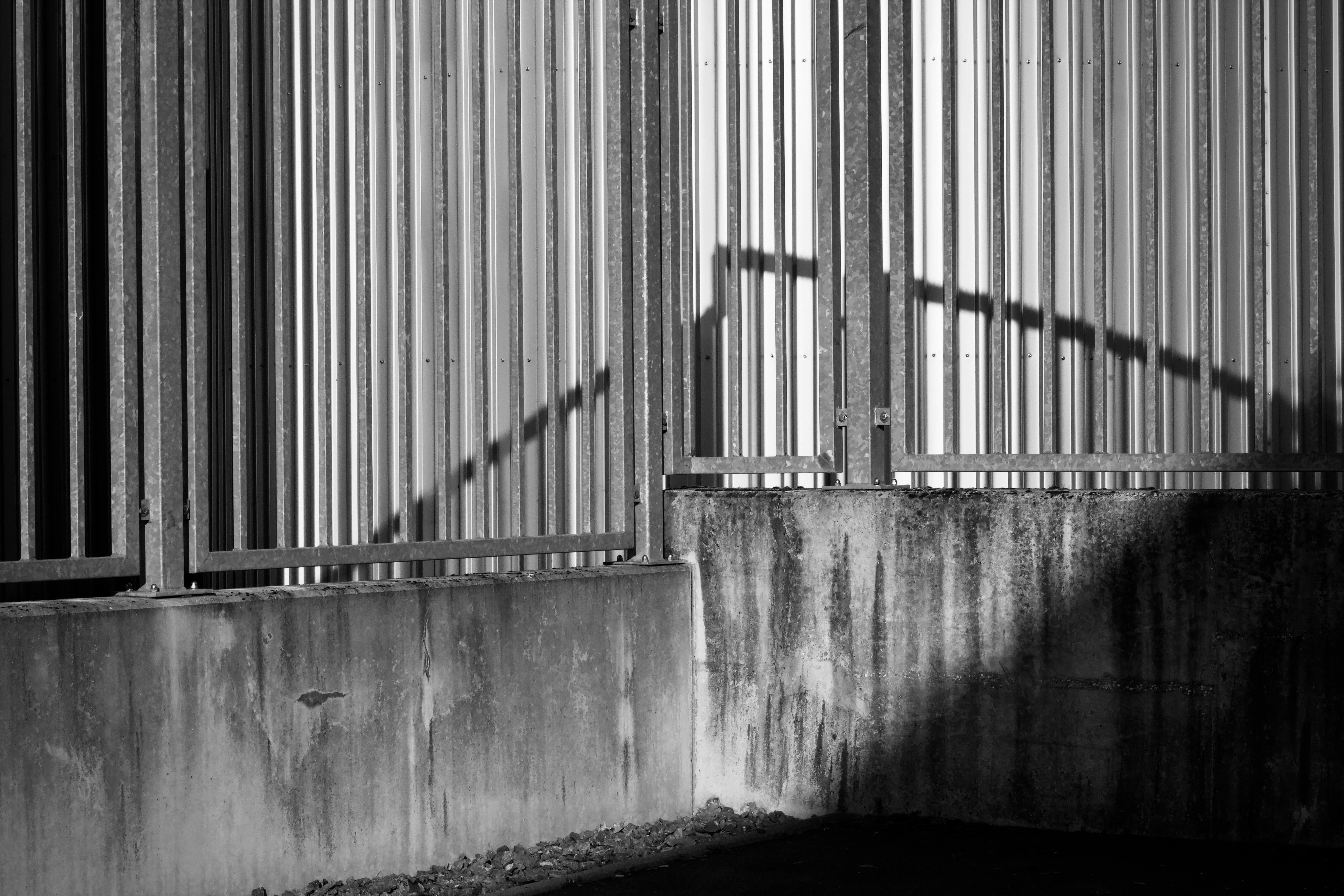 gratis Monochroom stedelijk compositieontwerp met structurele omheining en schaduwspel. Stockfoto