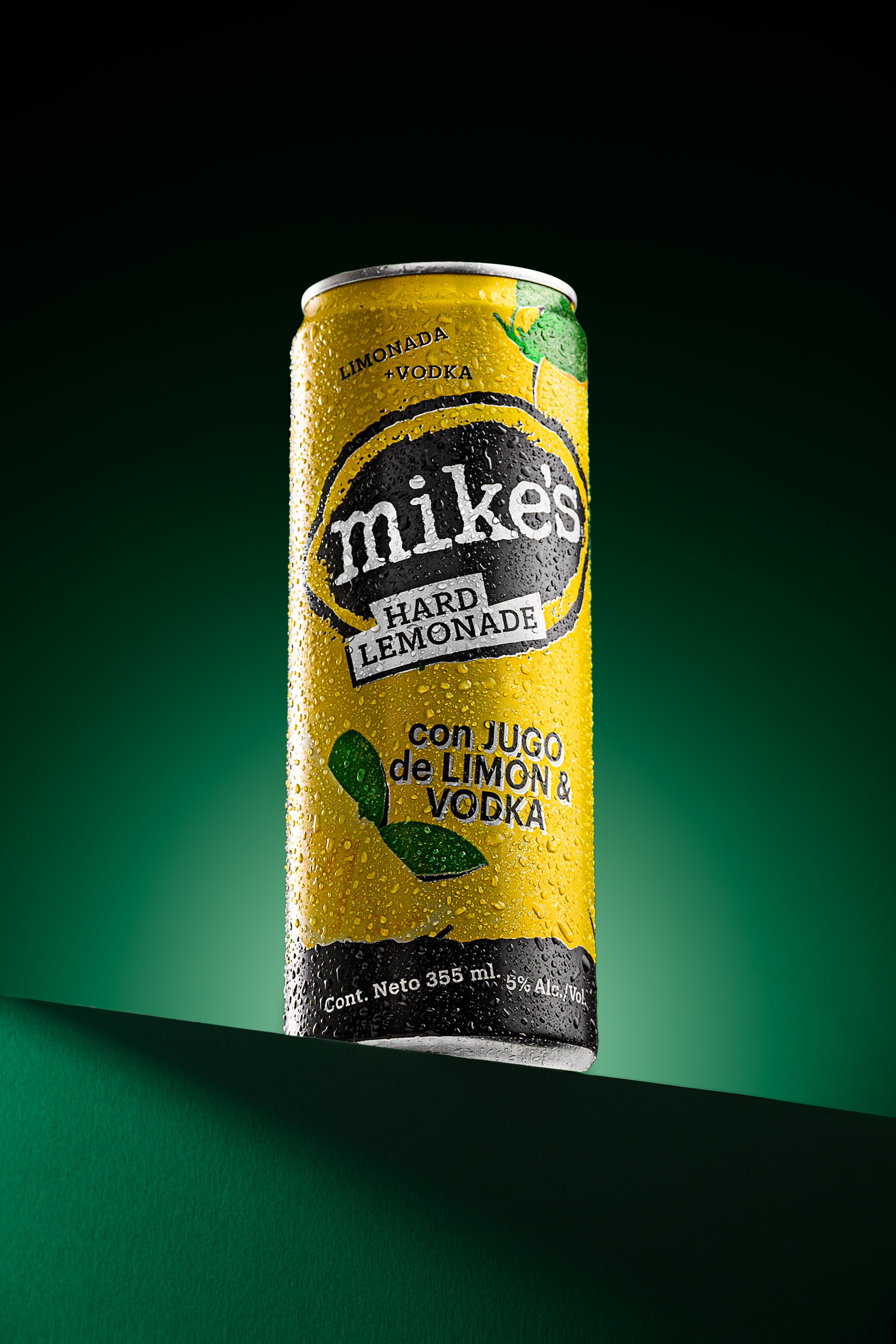 Studio shot of Mike's Hard Lemonade can with lime and vodka, on green background.