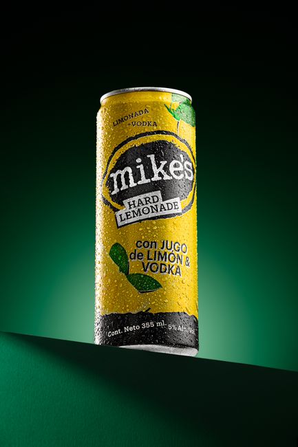 Studio shot of Mike's Hard Lemonade can with lime and vodka, on green background.