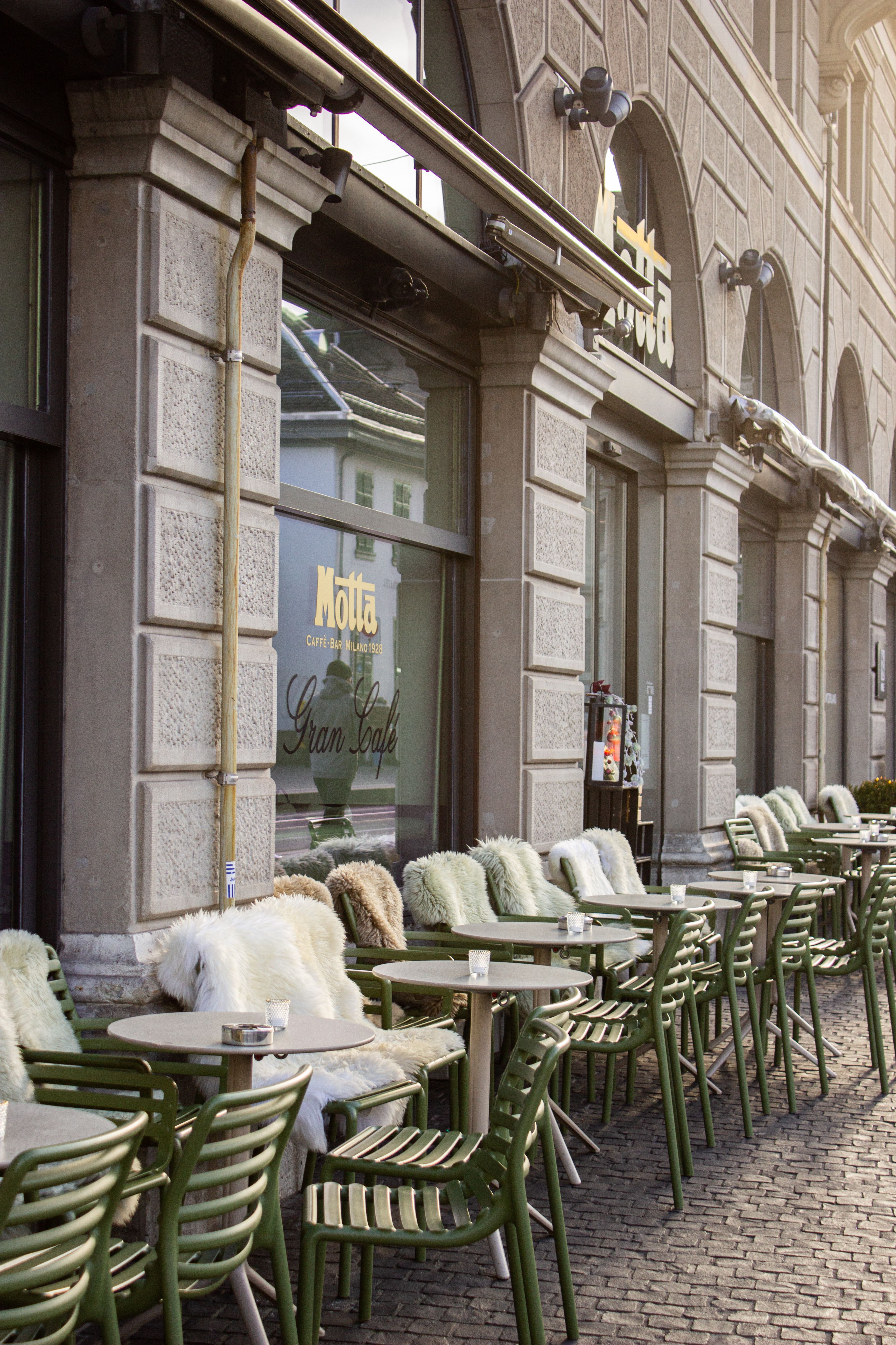 Cozy outdoor café seating with fur throw blankets in Zurich, featuring elegant architecture and inviting atmosphere.