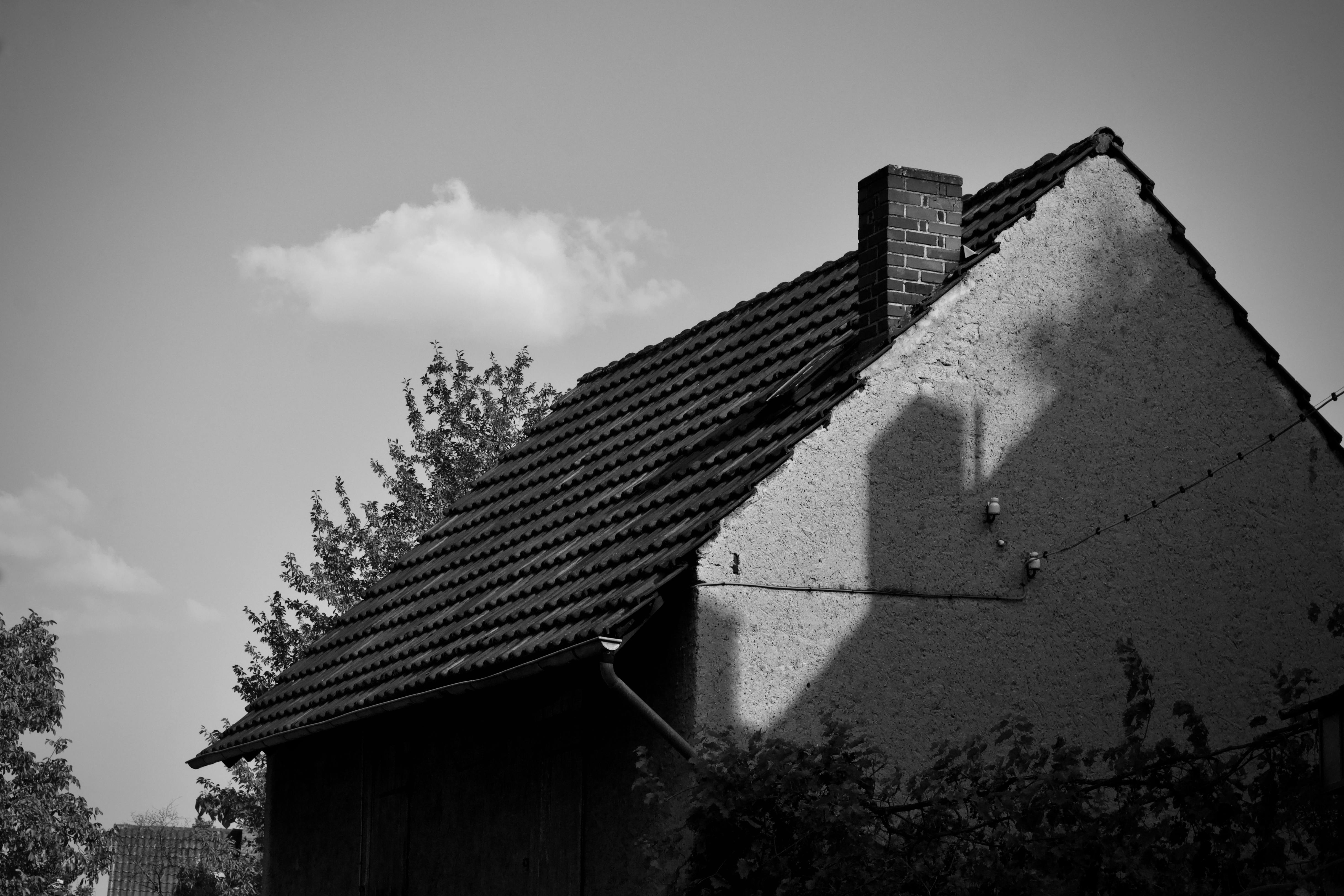 無料 晴れた空の下で影を落とす煙突のある家のモノクロ写真。 写真素材