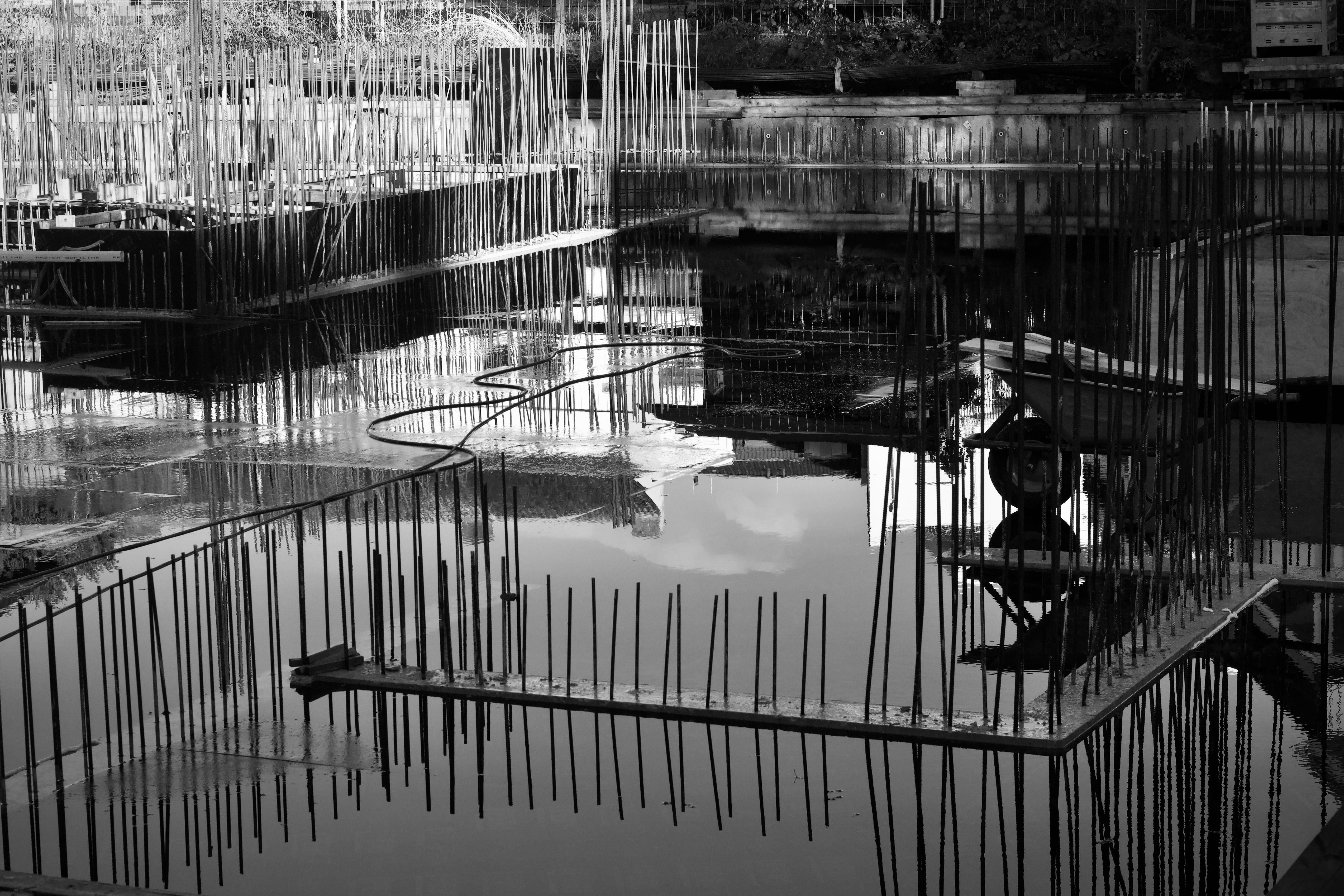 A black and white abstract image capturing construction site reflections in water.