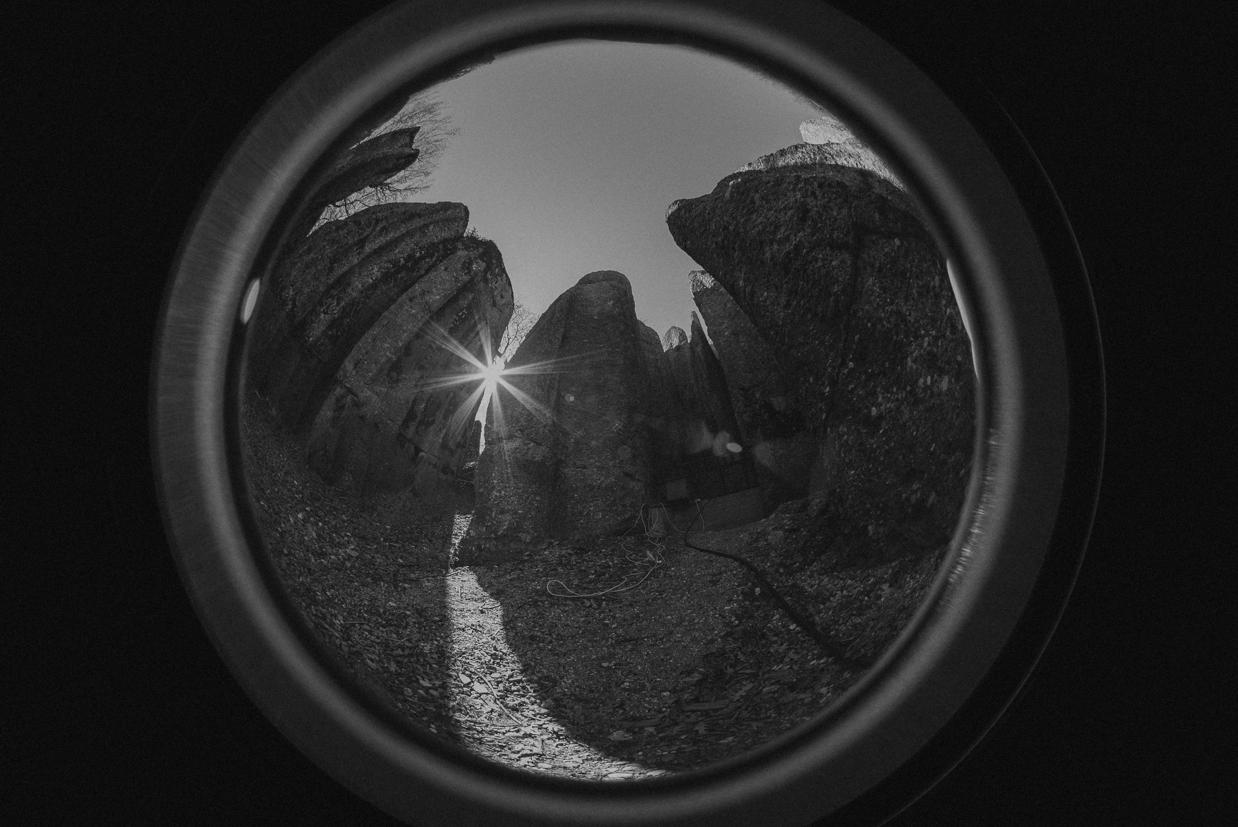 Kostnadsfria Solstrålning genom klippor fångad i ett dramatiskt svartvitt foto med fisheye. Stock foto