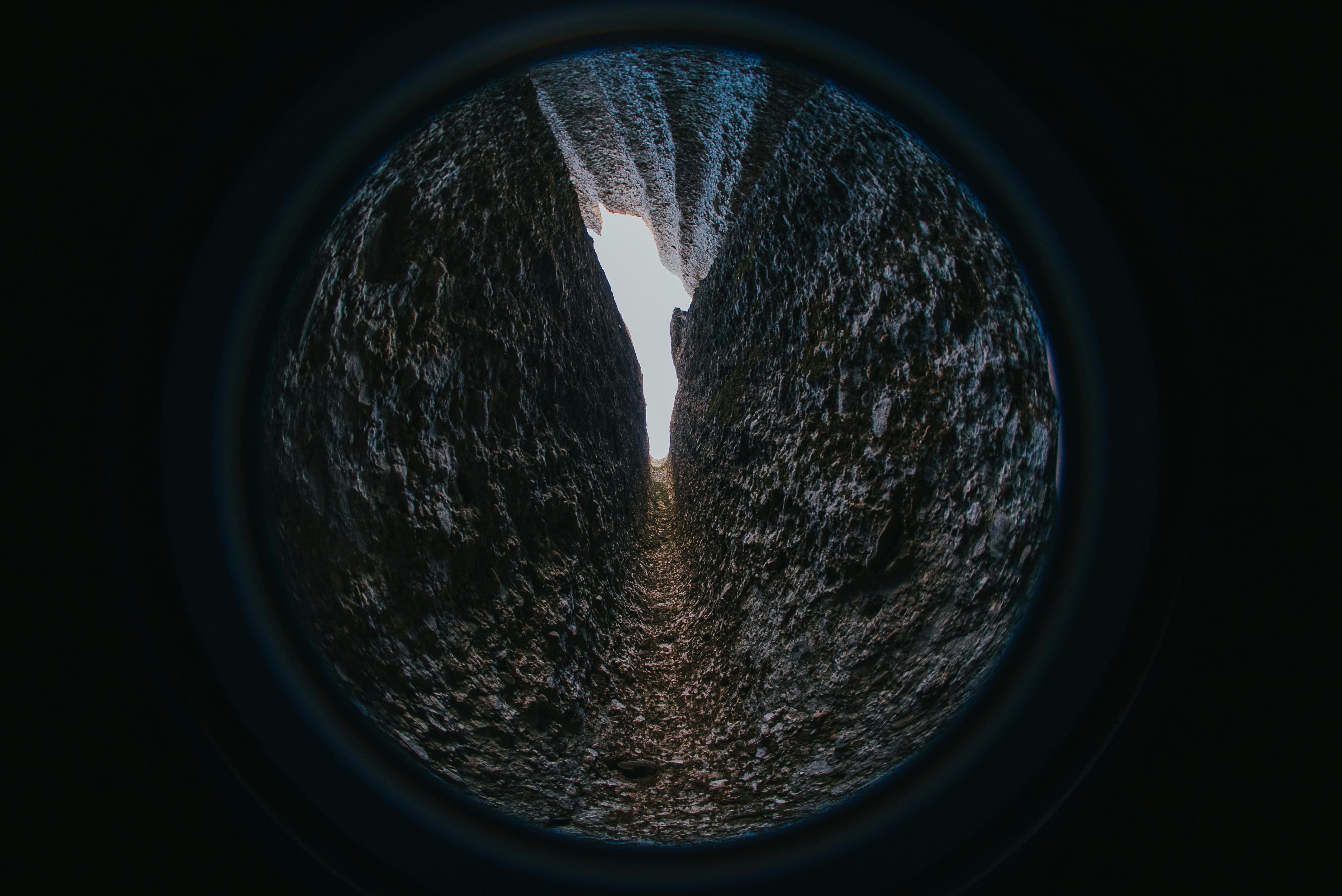Free A dramatic fisheye perspective of a narrow rock passageway leading to bright daylight. Stock Photo