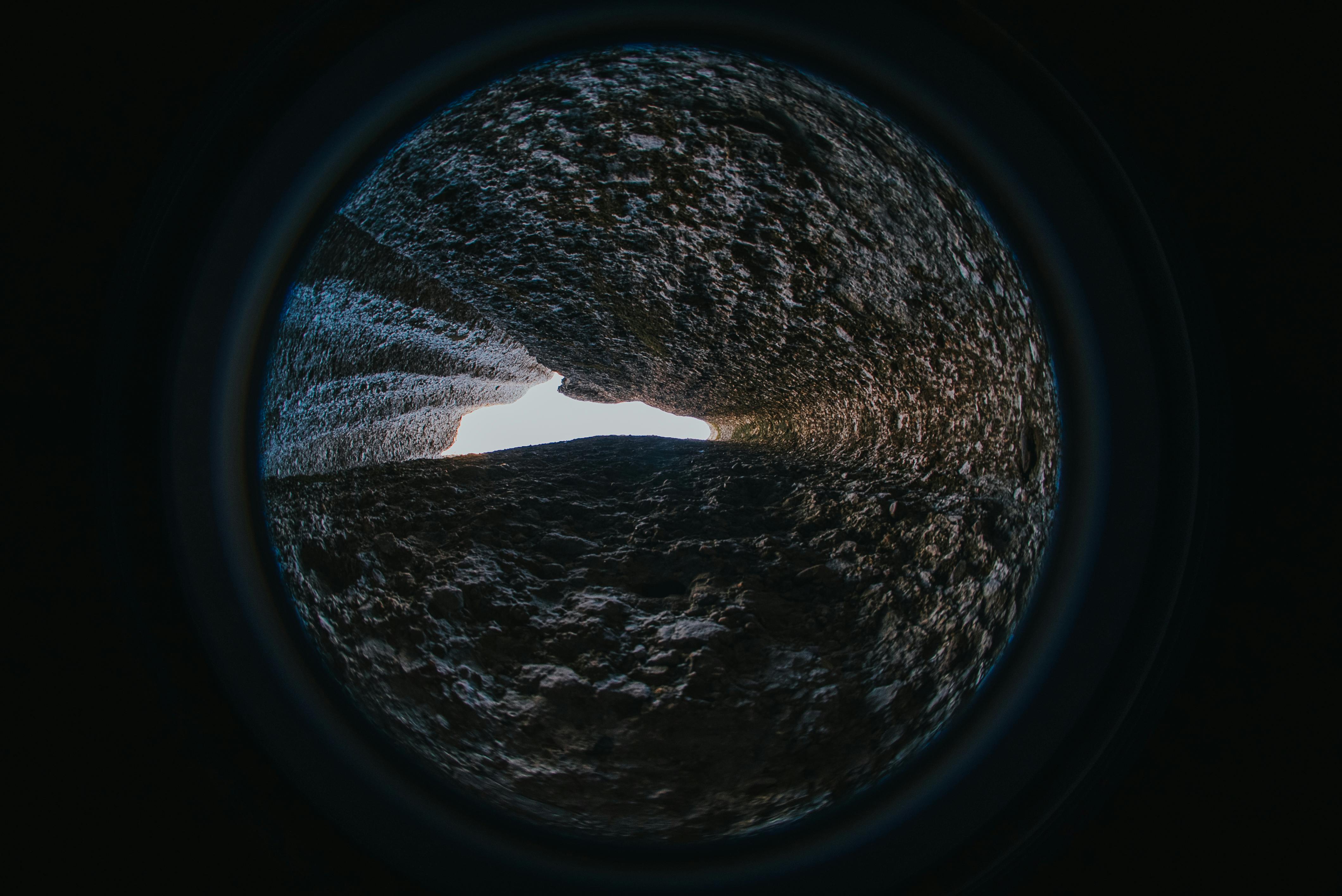 gratis Een uniek abstract perspectief door een ruw gestructureerde tunnel met licht aan het einde. Stockfoto