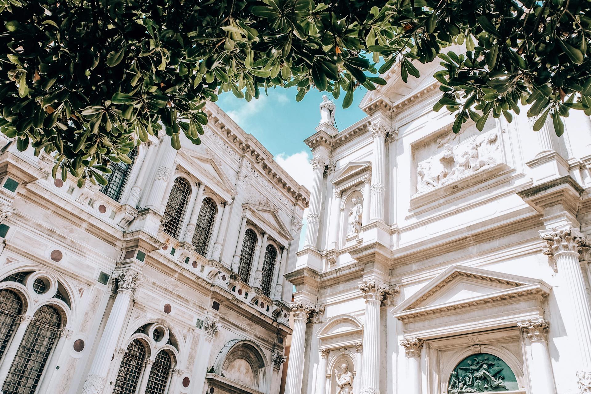 Stunning Renaissance building framed by lush green leaves on a sunny day.