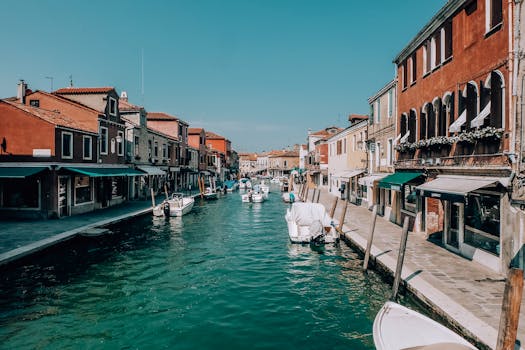 在晴朗的蓝天下，乘船探索威尼斯迷人的运河，欣赏沿岸历史悠久的建筑