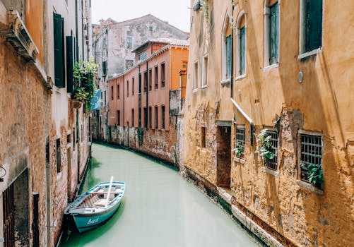 在明亮的日光下，威尼斯一条风景优美的运河边，停靠着船只，历史建筑静静矗立