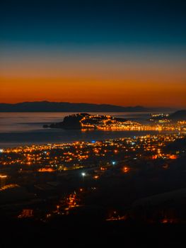 Breathtaking view of Alanya's coastline illuminated at sunset with city lights reflecting on the sea.