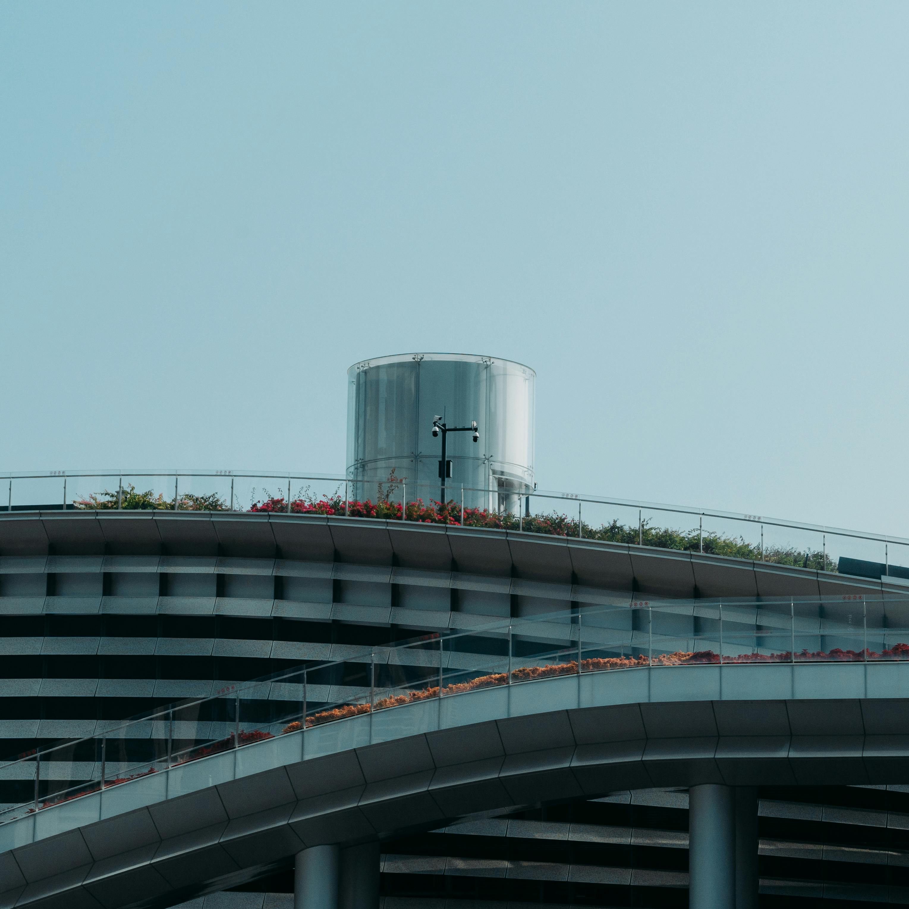 De franc Teulada arquitectònica elegant amb una ventilació circular, baranes de vidre i vegetació sota un cel blau clar. Foto d'estoc