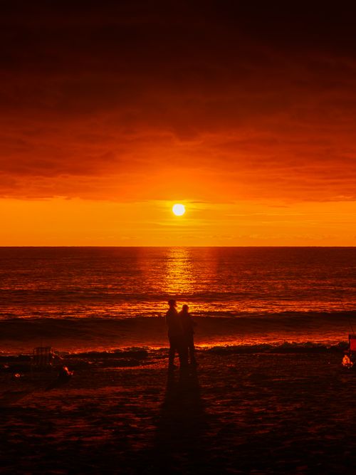 Free Couple enjoying a vivid sunset on Mahmutlar Beach, Antalya, Turkey. Stock Photo